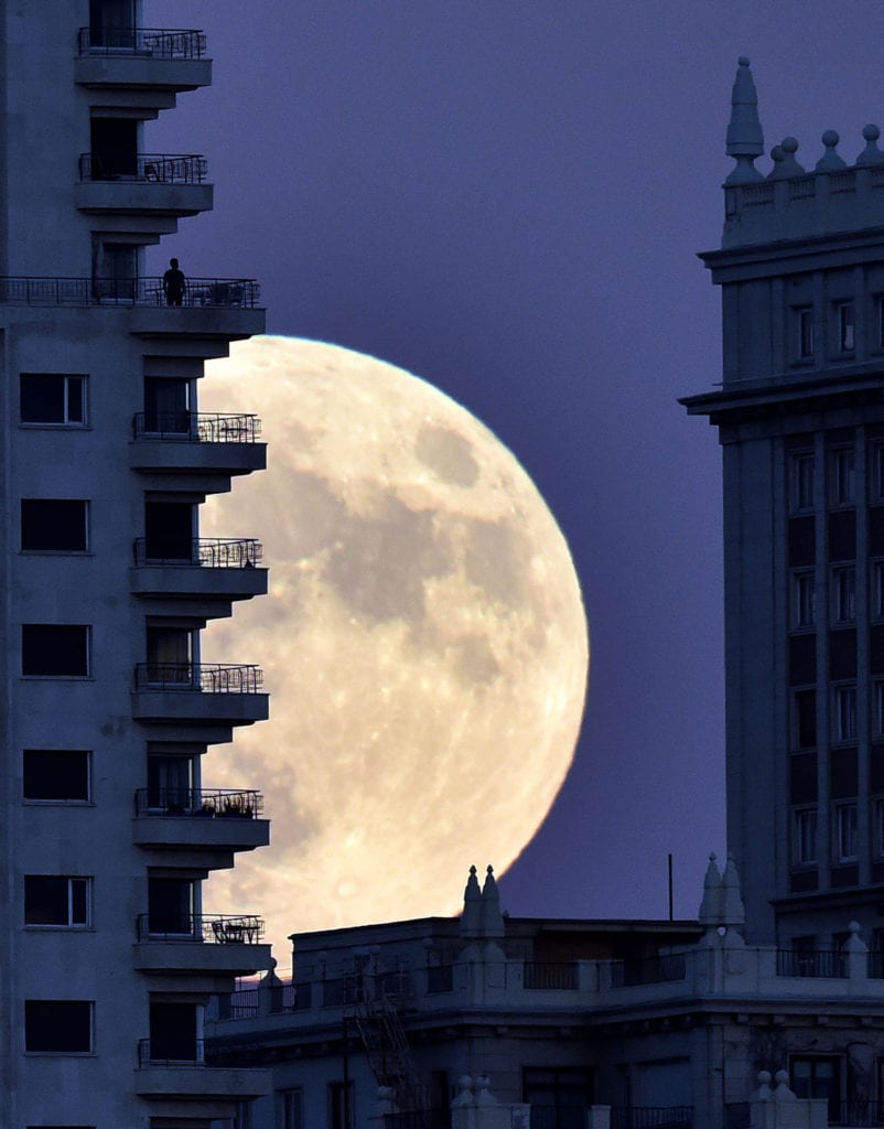 Un hombre se ve en un balcón de un edificio de Madrid como la luna se eleva en el fondo, el 13 de noviembre de 2016, en la víspera de una superluna.
